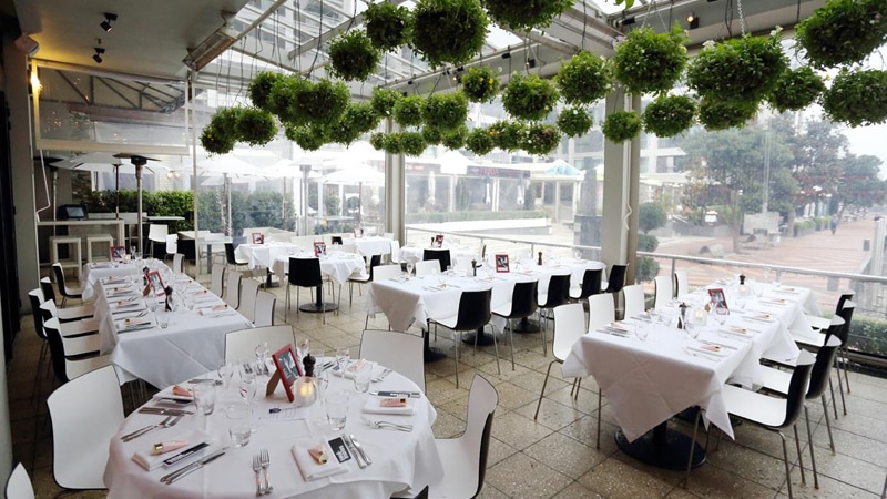 elegant white and black themed open window restaurant with green hanging plants