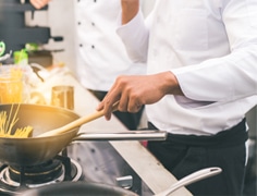 chef wearing a white uniform cooking pasta