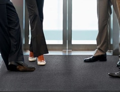 employee stepping on a black entrance mat